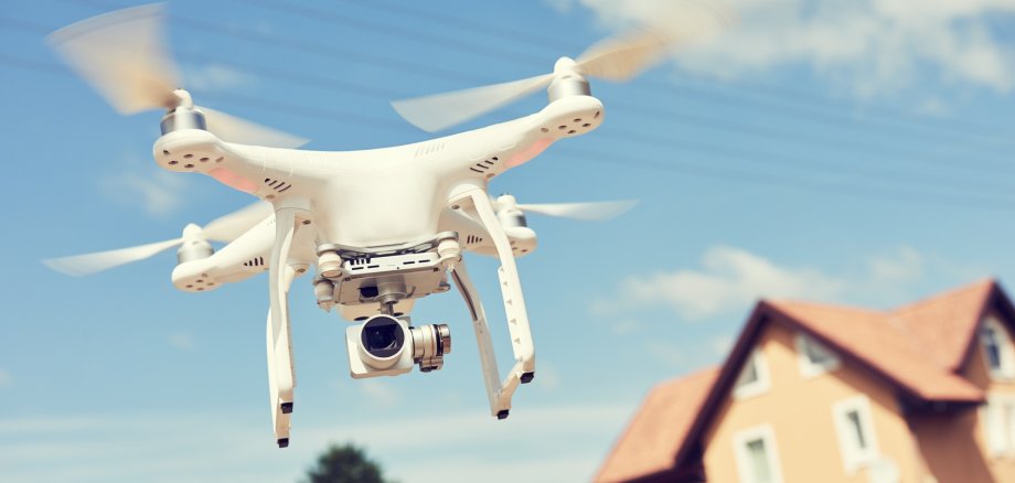 Drohne mit Kamera fliegt über Häusersiedlung. 