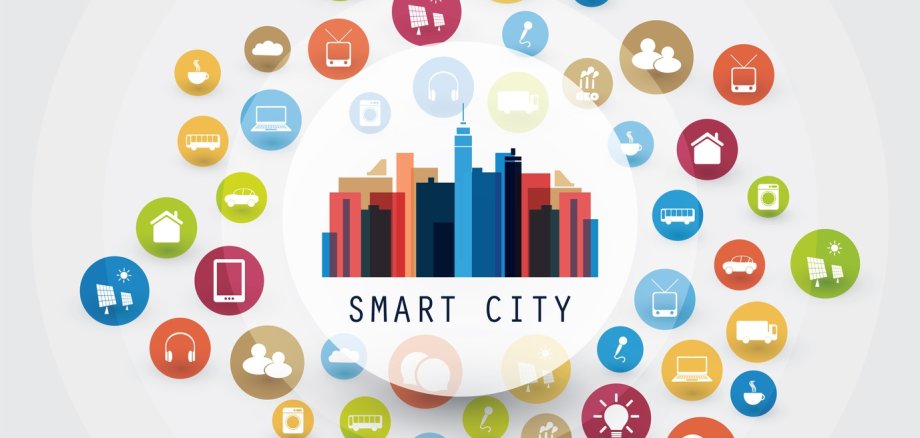 In der Mitte eines grau-weißen Kreises steht das Wort "Smart City" mit einem geschrieben. Über Smart City ist die Skylinie einer Stadt abgebildet. Um die Smart City sind viele Kreise mit Symbolen einer digitalen Stadt abgebildet.