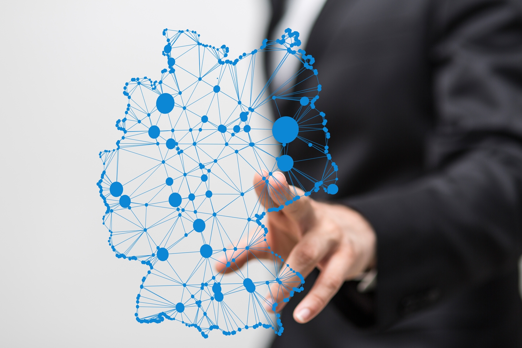 Mann zeigt auf blaue Deutschlandkarte in der Luft, in welcher blaue Punkte mit blauen Strichen verbunden sind.