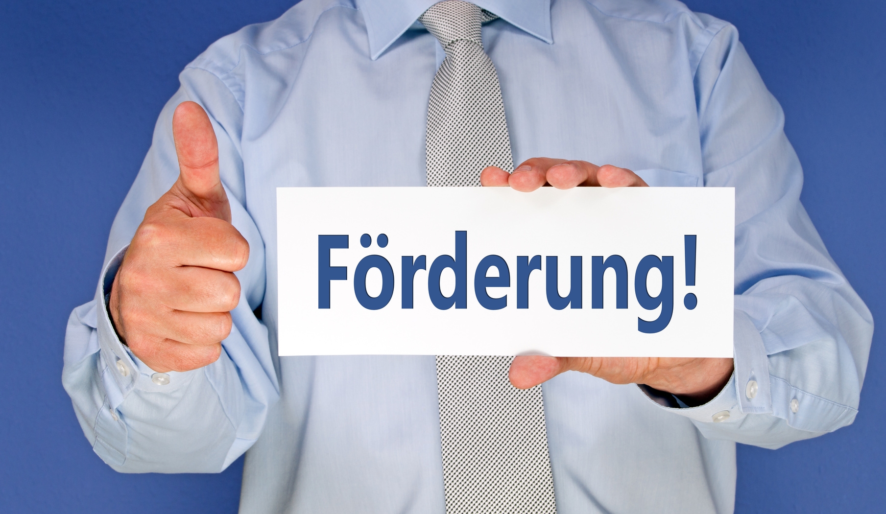 Ein mit Hemd und Krawatte gekleideter Mann hält vor seinen Brustkorb ein Schild mit der Aufschrift Förderung!  Ein mit Hemd und Krawatte gekleideter Mann hält vor seinen Brustkorb ein Schild mit der Aufschrift Förderung!