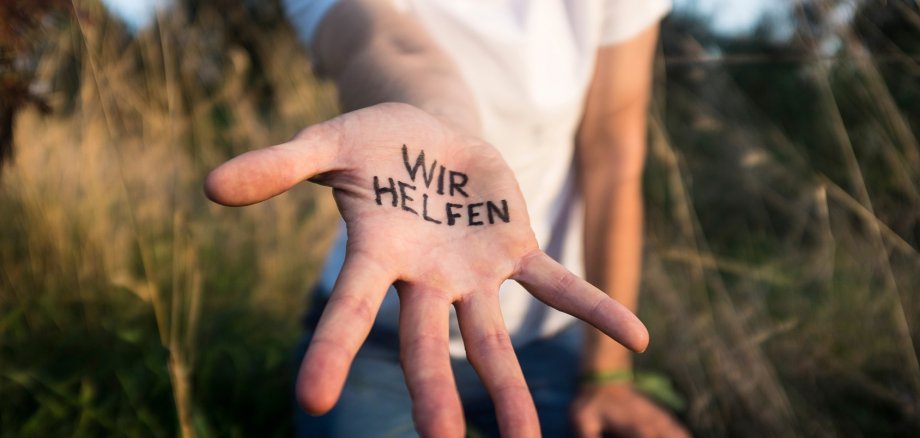 Eine offene Hand mit der Aufschrift "Wir helfen!"