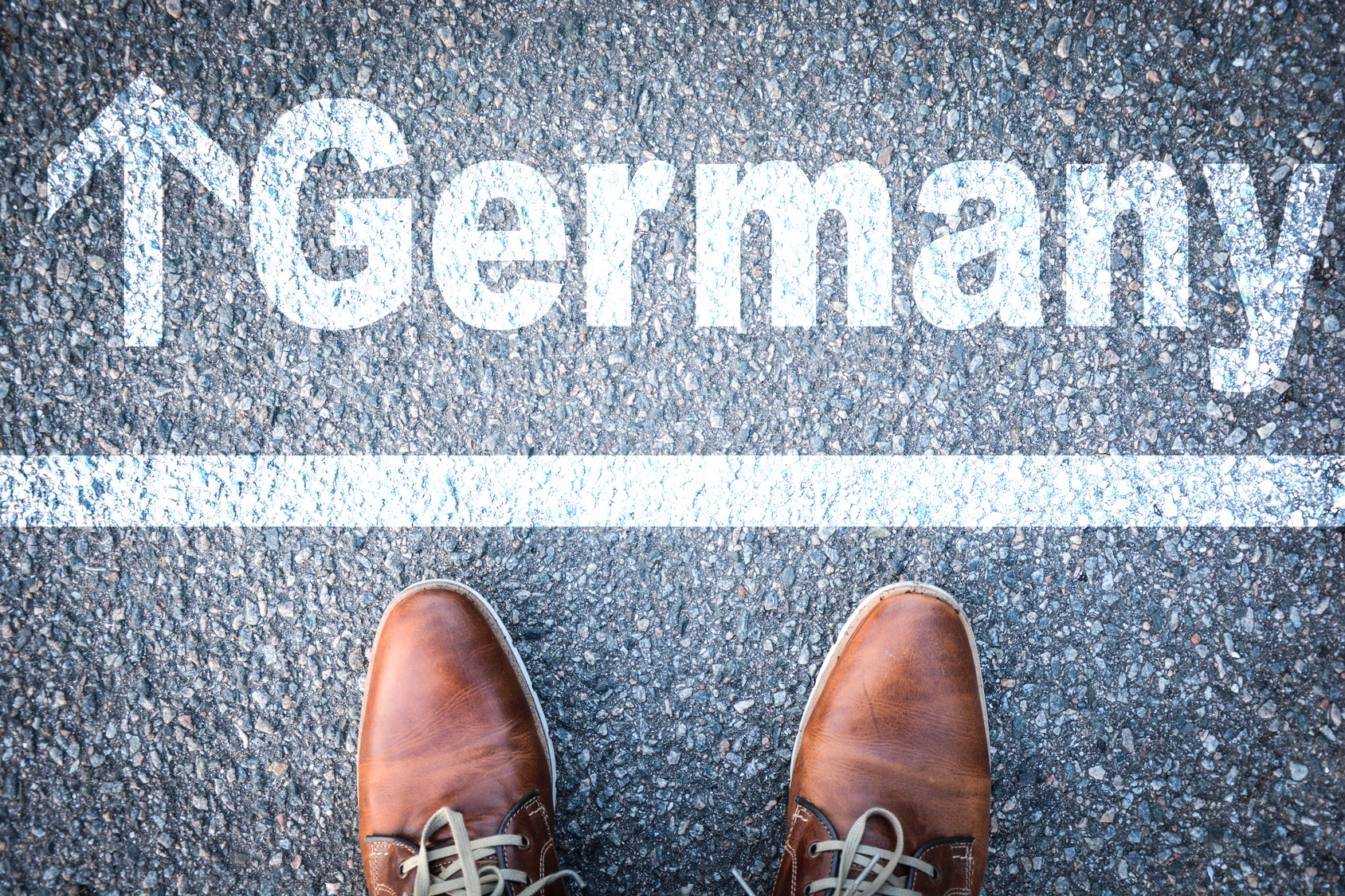 Ein zweigeteiltes Bild: Unten sind Schuhe eines Mannes zu sehen und im oberen Teil des Bildes das Wort Germany mit einem Pfeil nach vorne  Ein zweigeteiltes Bild: Unten sind Schuhe eines Mannes zu sehen und im oberen Teil des Bildes das Wort Germany mit einem Pfeil nach vorne
