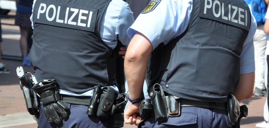 Zwei Polizisten in Uniform und mit Waffen nebeneinander.