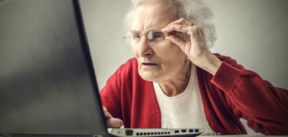 Alte Frau vor Laptop, die Schwierigkeiten hat.