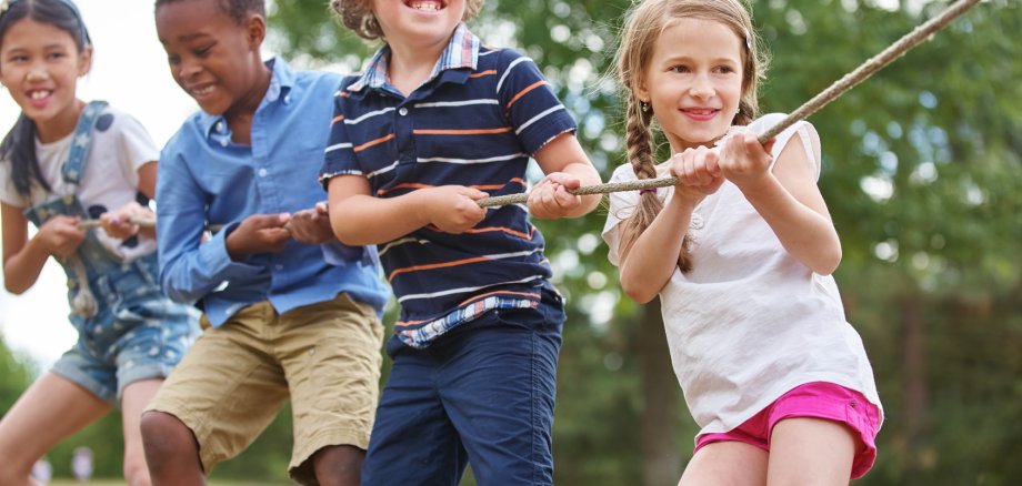 Kinder, die gemeinsam an einem Tau ziehen.