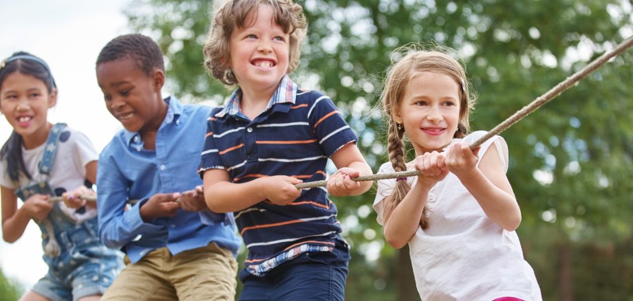 Kinder, die gemeinsam an einem Tau ziehen.