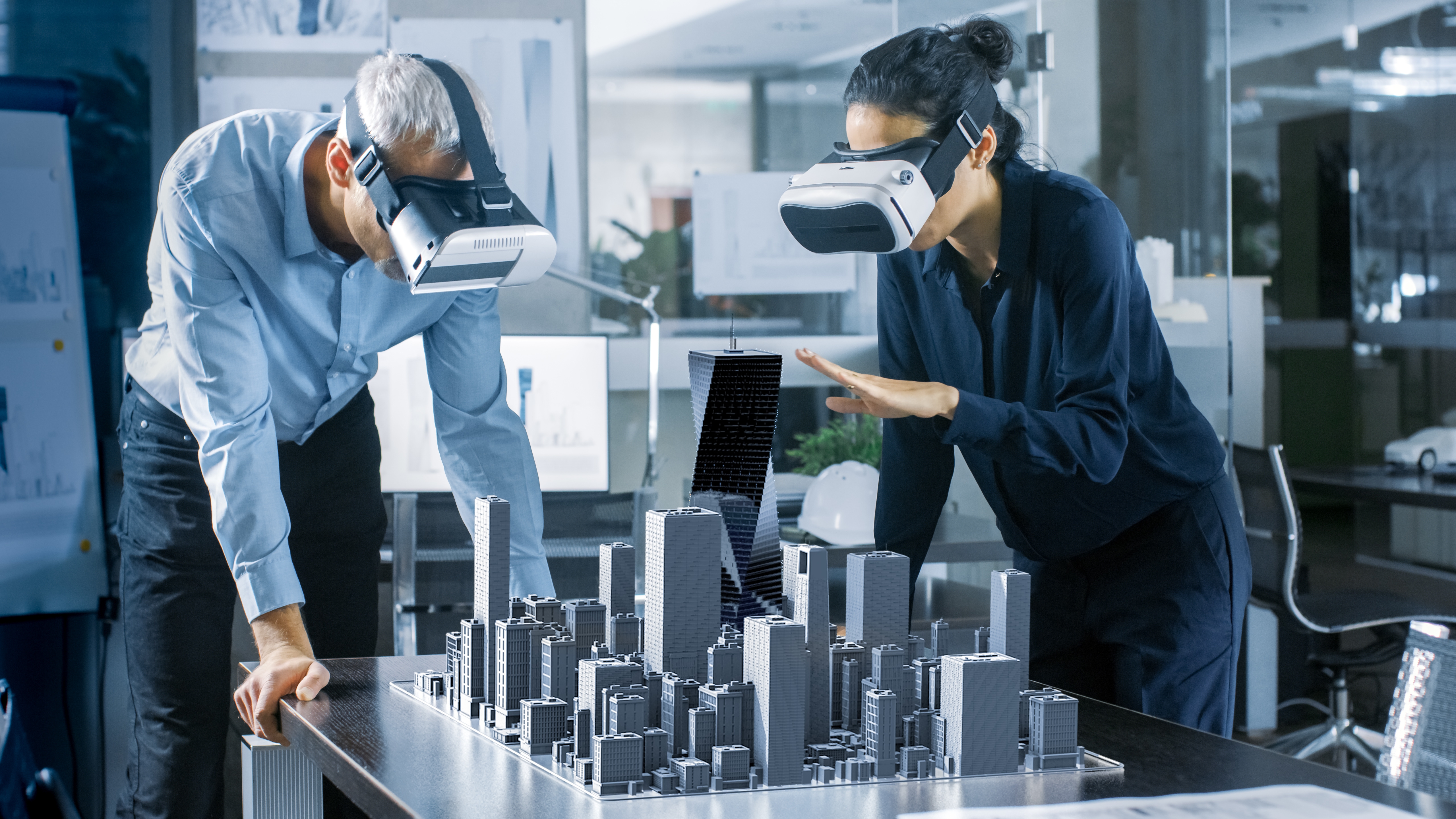 Frau und Mann, die VR-Brillen tragen und sich ein 3D-Stadtmodell anschauen. Frau und Mann, die VR-Brillen tragen und sich ein 3D-Stadtmodell anschauen.
