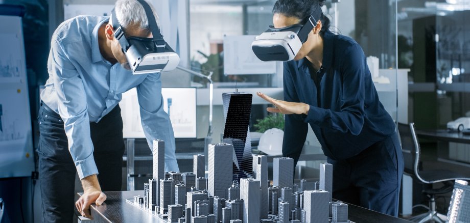Frau und Mann, die VR-Brillen tragen und sich ein 3D-Stadtmodell anschauen.