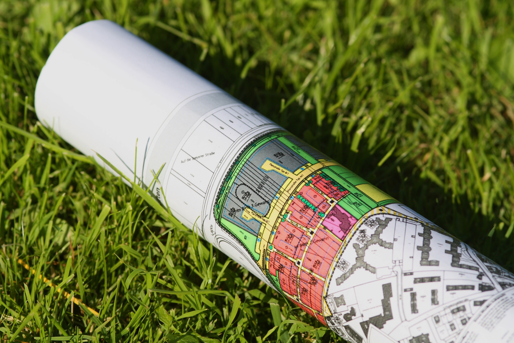 Städtebauskizze/Karte zusammengerollt auf Gras Städtebauskizze/Karte zusammengerollt auf Gras