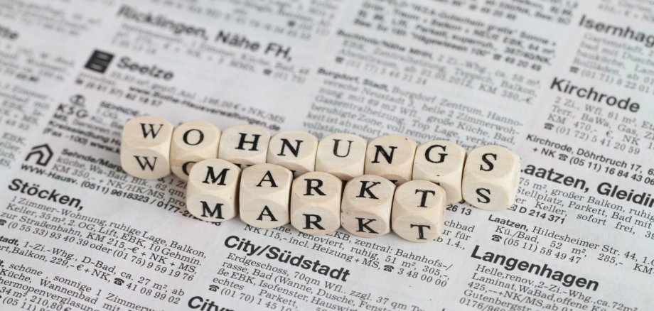 Buchstabenwürfel, die das Wort "Wohnungsmarkt" bilden auf einer Zeitung