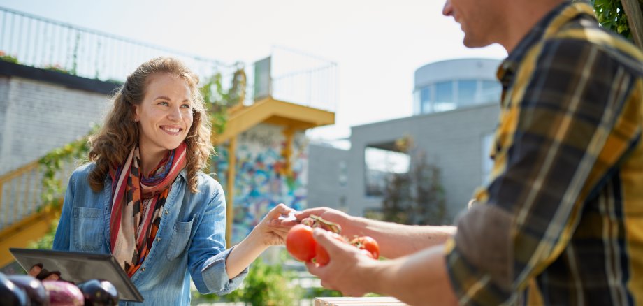 Eine Frau und ein Mann am Obst- und Gemüsestand eines Wochenmarktes