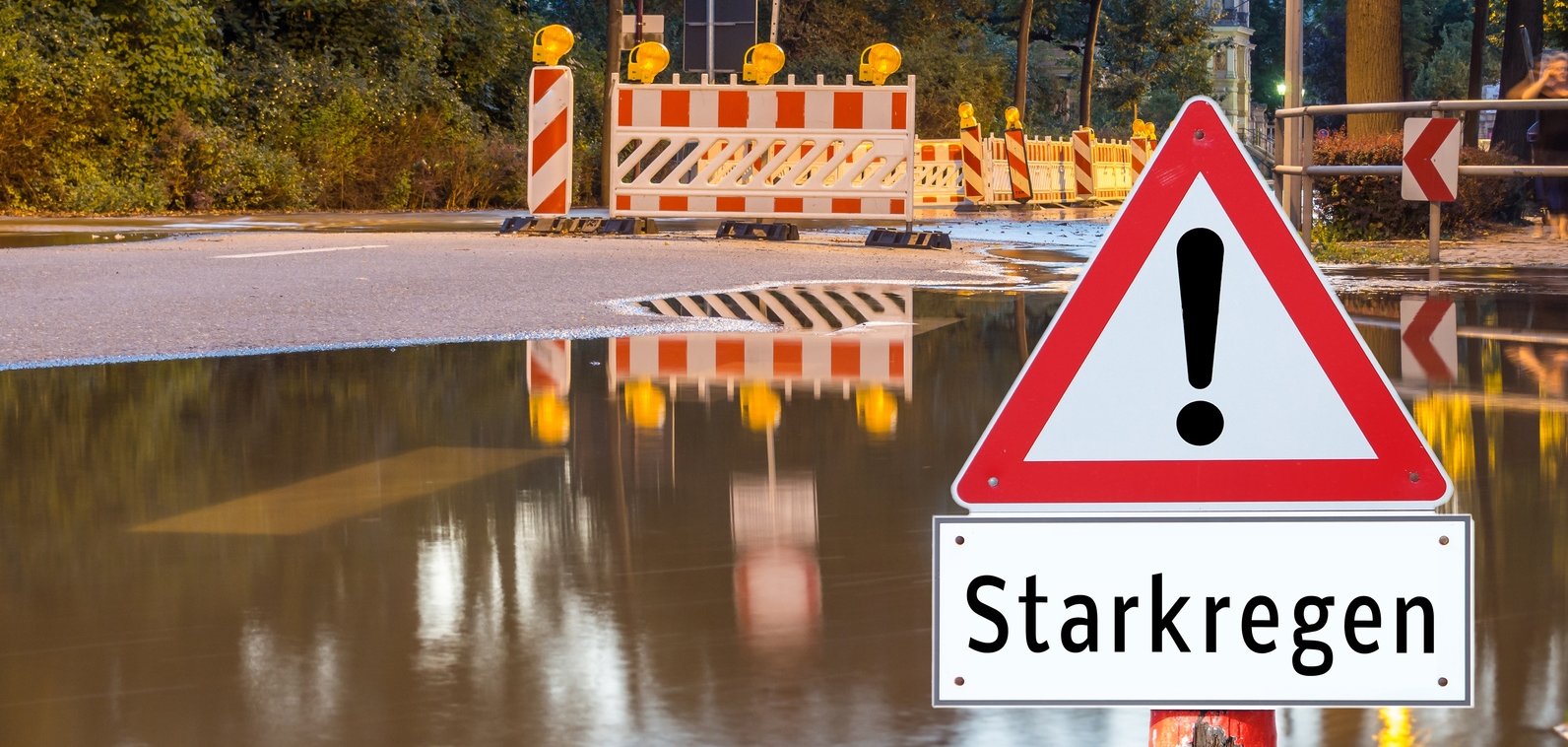 Überschwemmte Straße mit Warnschild Starkregen
