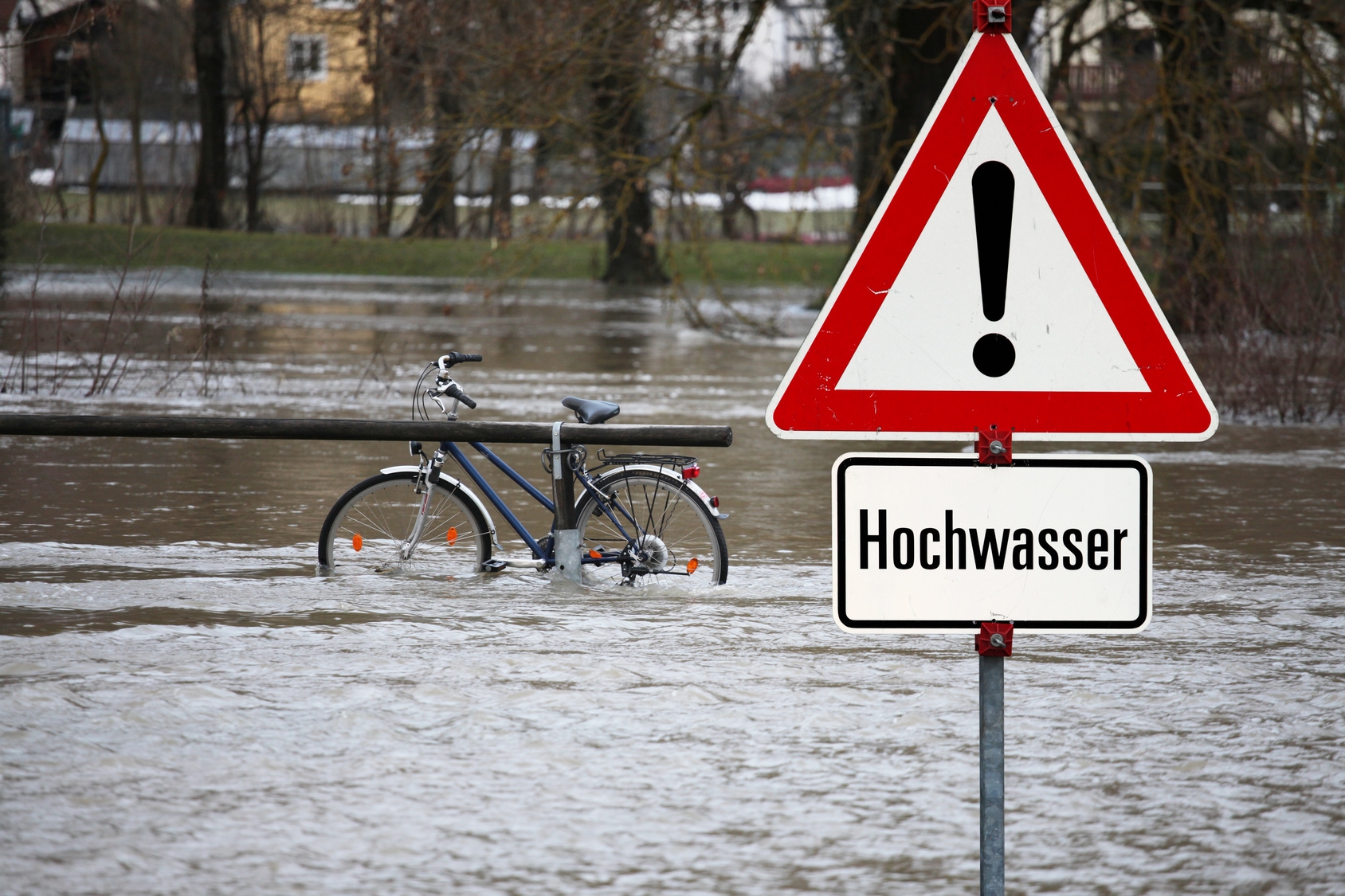 Hochwasserschild auf überschwemmter Straße  Hochwasserschild auf überschwemmter Straße