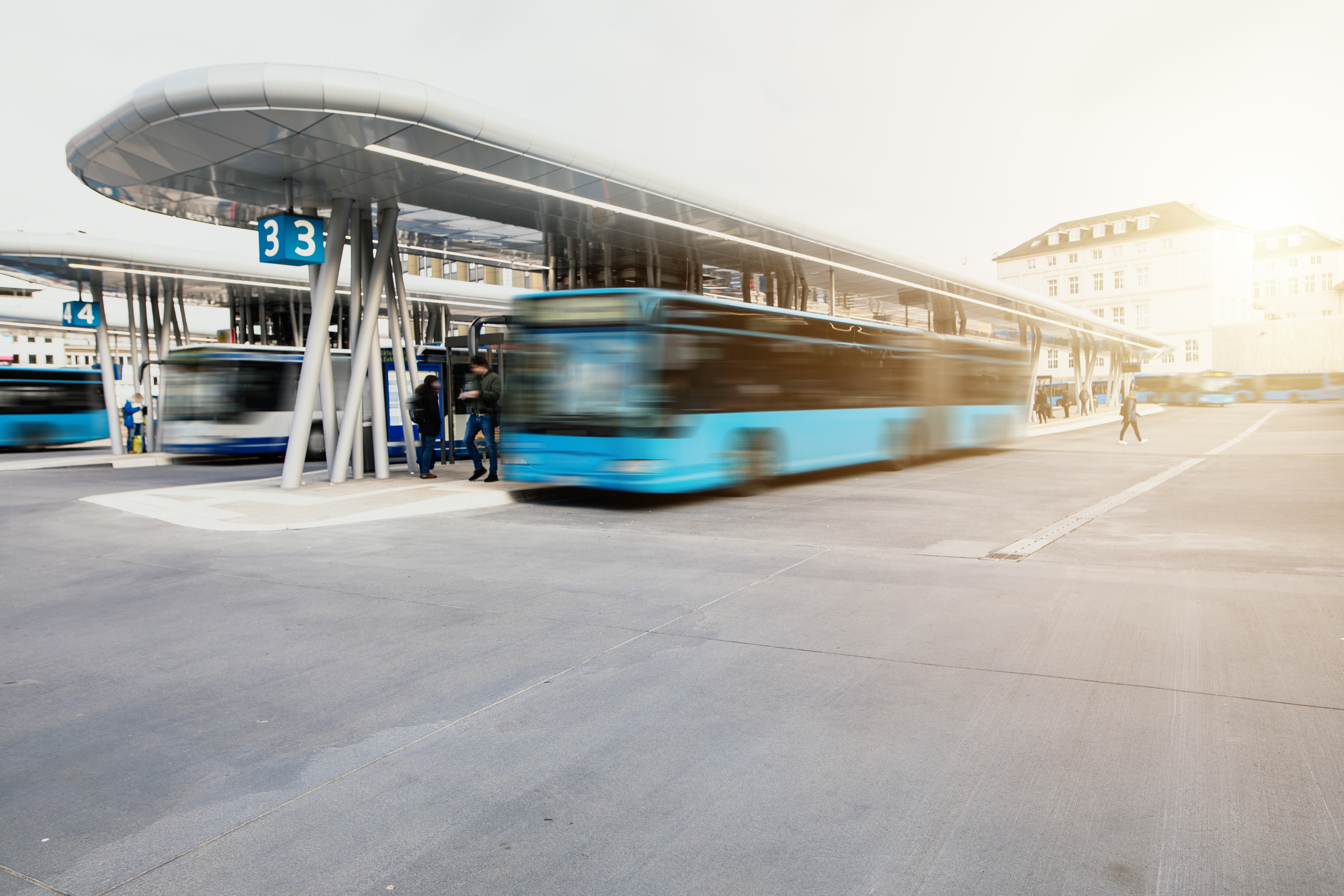 Bus fährt von der Bushaltestelle am modernen Busbahnhof los Bus fährt von der Bushaltestelle am modernen Busbahnhof los