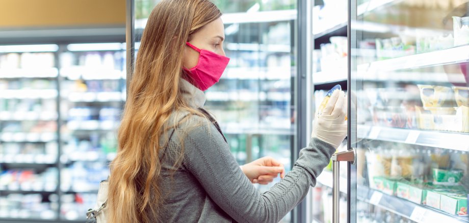 Frau beim Einkaufen im Supermarkt mit Mund-Nasen-Schutz