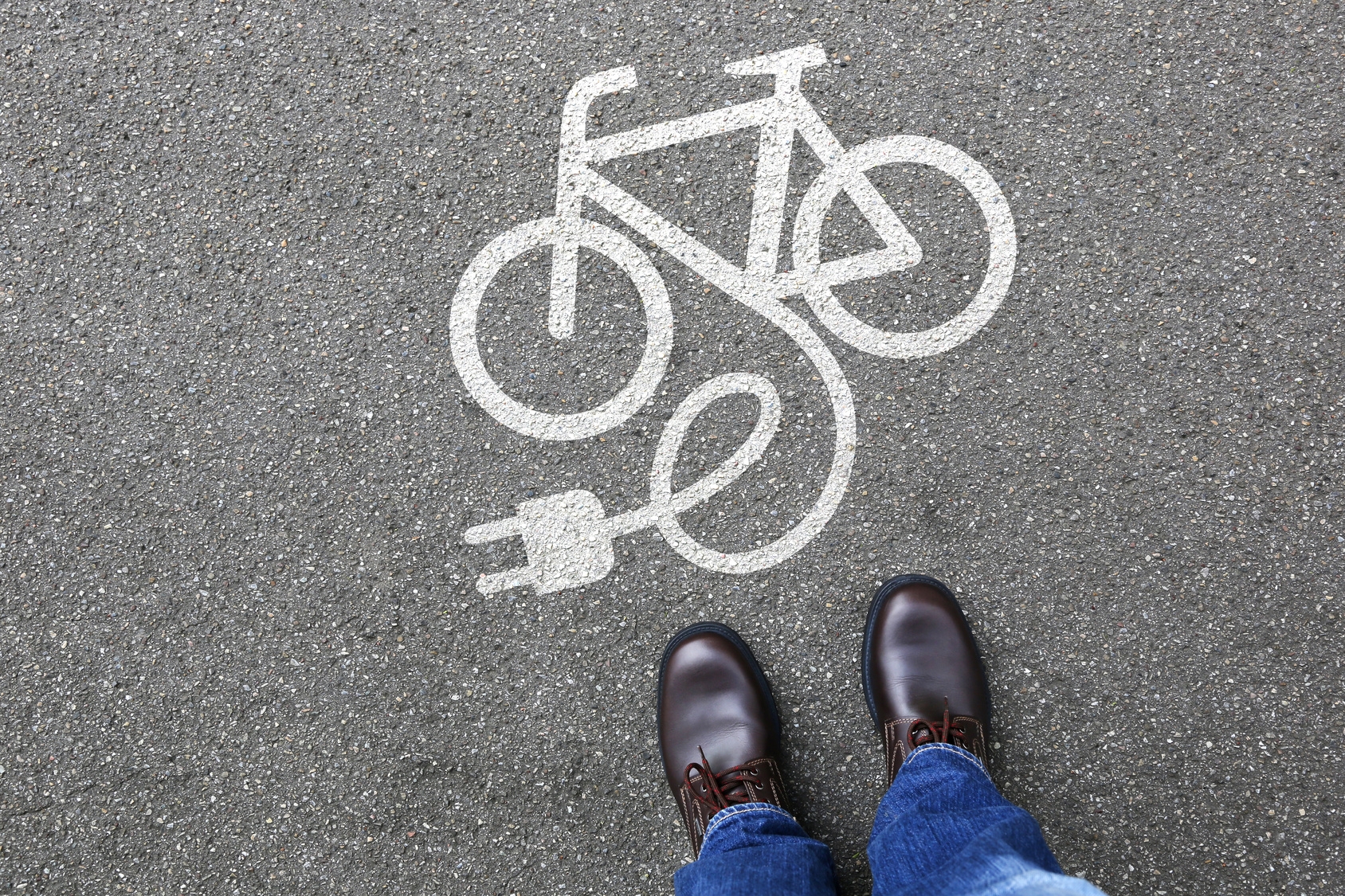 E-Bike Symbol auf der Straße, Person steht davor