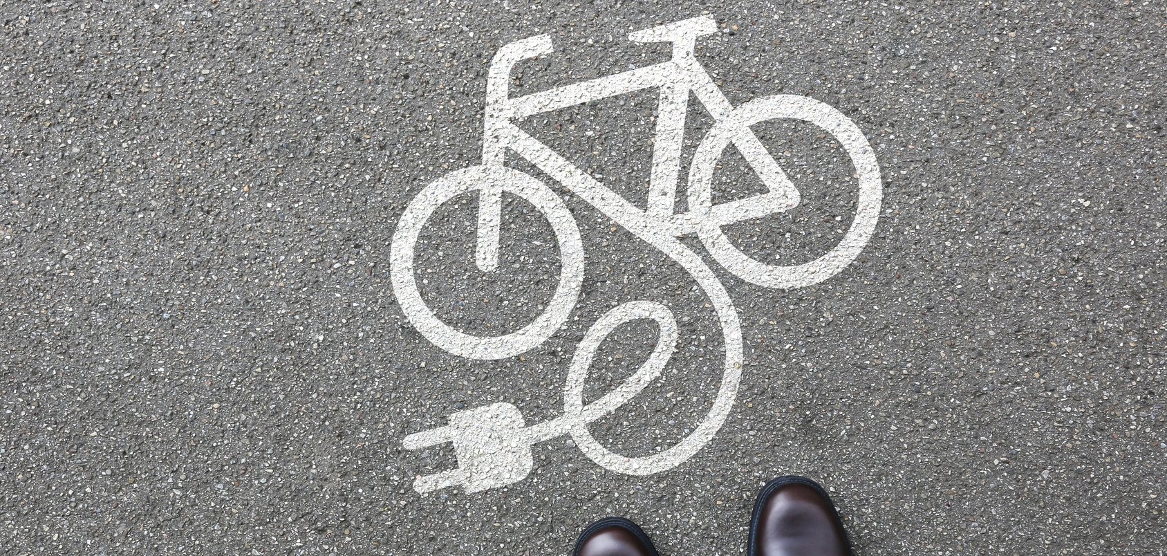 E-Bike Symbol auf der Straße, Person steht davor E-Bike Symbol auf der Straße, Person steht davor