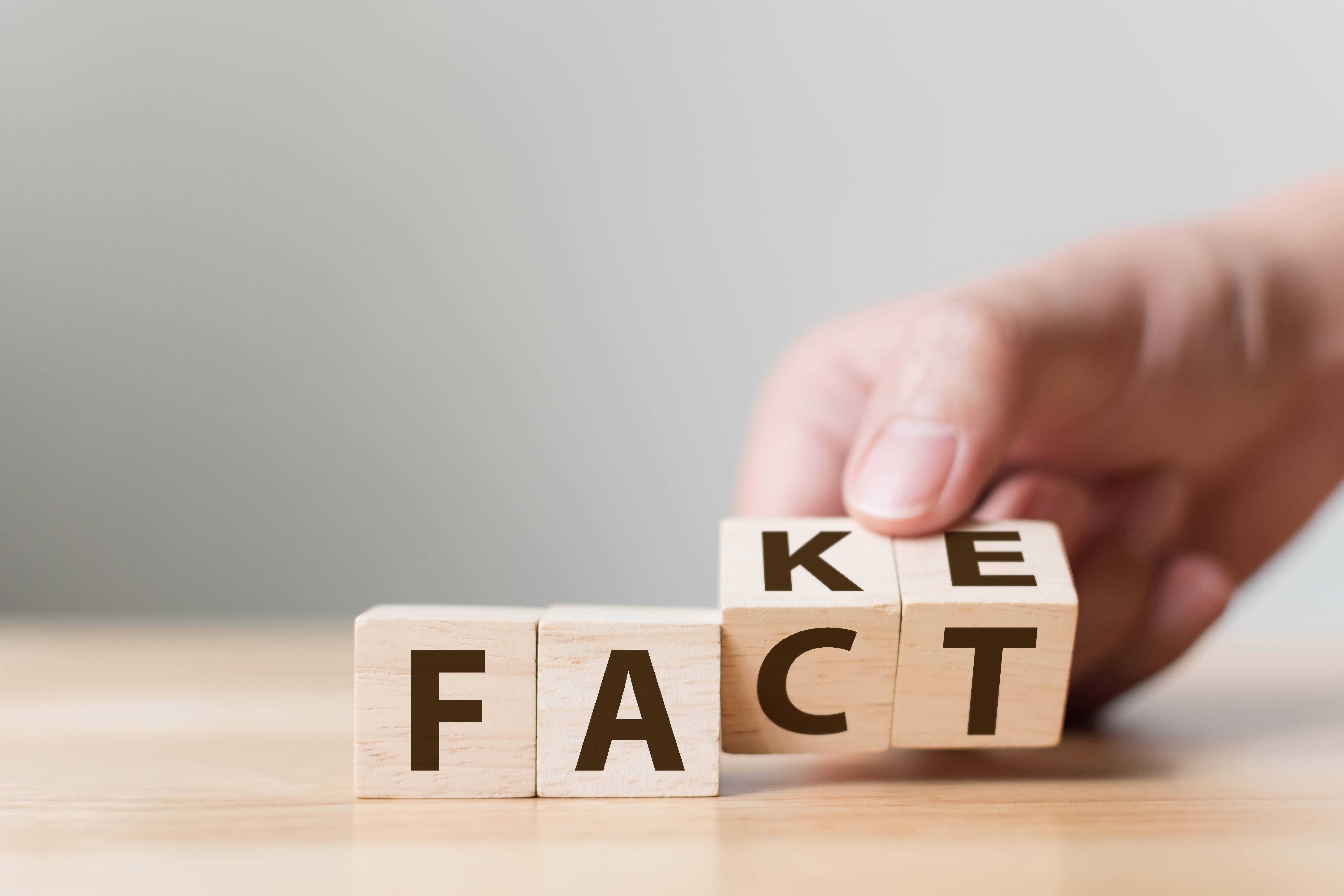 Auf Würfeln stehen die Worte "Fact" und "Fake". Eine Hand dreht die letzten beiden Würfel und verändert so das Wort. Auf Würfeln stehen die Worte "Fact" und "Fake". Eine Hand dreht die letzten beiden Würfel und verändert so das Wort.