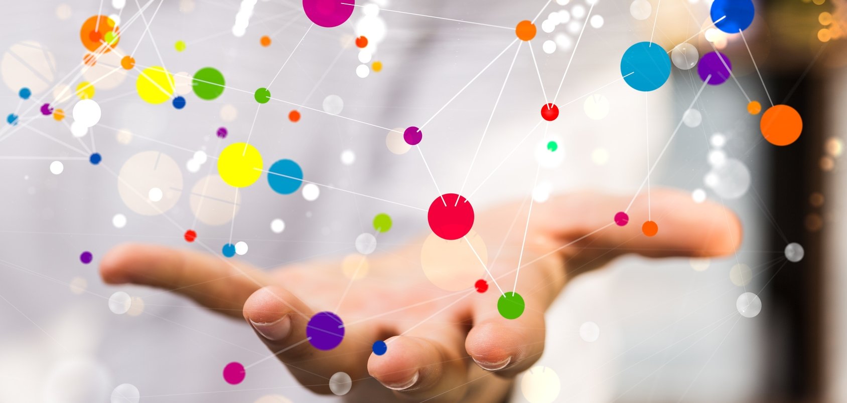 Eine nach vorne ausgestreckte Hand über der eine Vielzahl verschieden großer Punkte abgebildet sind, welche durch weiße Linien verbunden sind. Eine nach vorne ausgestreckte Hand über der eine Vielzahl verschieden großer Punkte abgebildet sind, welche durch weiße Linien verbunden sind.