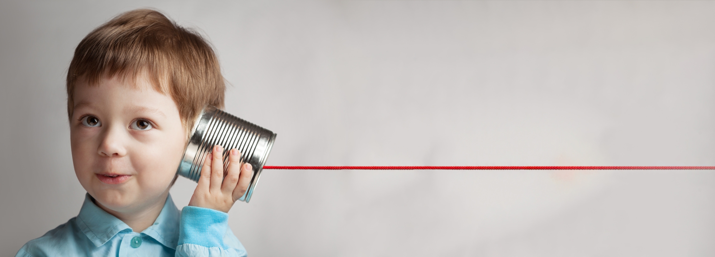 Kleiner Junge hält ein Dosentelefon mit roter Schnur ans Ohr. Kleiner Junge hält ein Dosentelefon mit roter Schnur ans Ohr.