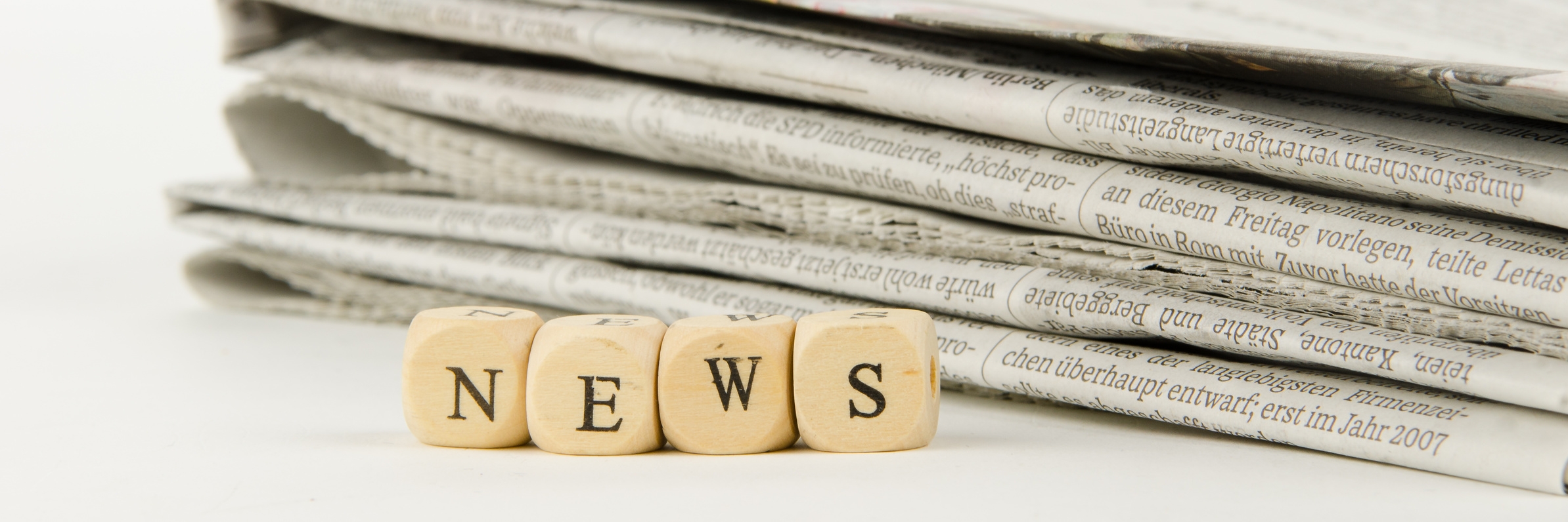 Beschriftete Würfel bilden das Wort "News". Im Hintergrund liegt ein Stapel an Zeitschriften. Beschriftete Würfel bilden das Wort "News". Im Hintergrund liegt ein Stapel an Zeitschriften.
