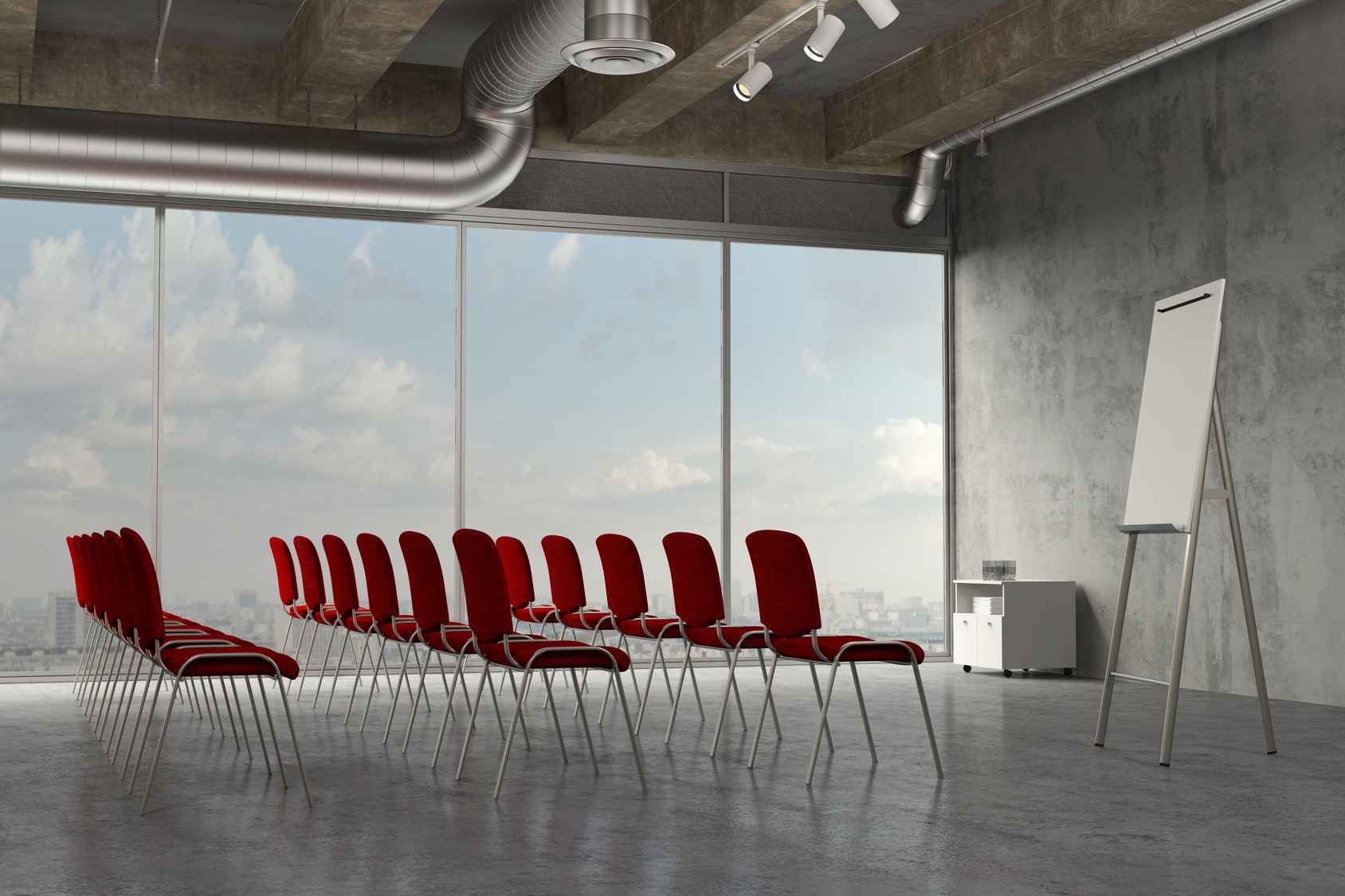 Konferenzraum mit Stuhlreihen mit roten Stühlen. Davor steht ein Flipchart.