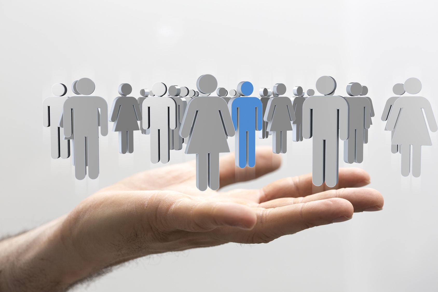 Über einer ausgestreckten Hand schweben zahlreiche graue Symbolbilder für Mann und Frau. Eine männliches Symbolbild ist anstatt grau, blau hervorgehoben.