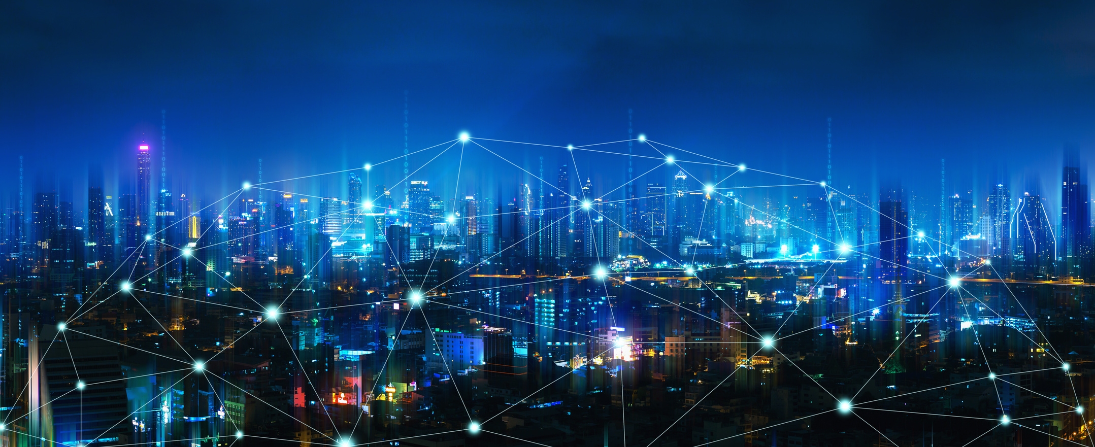 Vor der Skyline einer Stadt bei Nacht sind Punkte miteinanderverbunden. Symbolbild für eine Smart City. Vor der Skyline einer Stadt bei Nacht sind Punkte miteinanderverbunden. Symbolbild für eine Smart City.