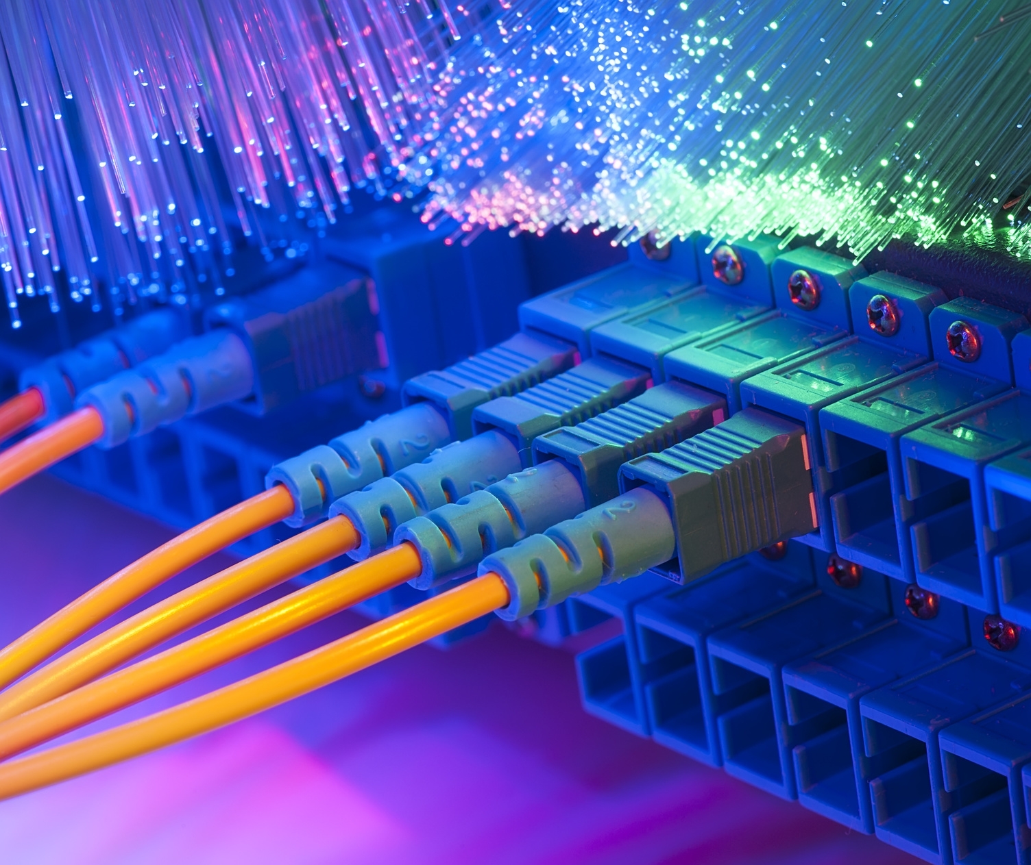 Vier Kabel sind an einem Rechner angeschlossen und darüber befinden sich offene Glasfaserkabel. Vier Kabel sind an einem Rechner angeschlossen und darüber befinden sich offene Glasfaserkabel.