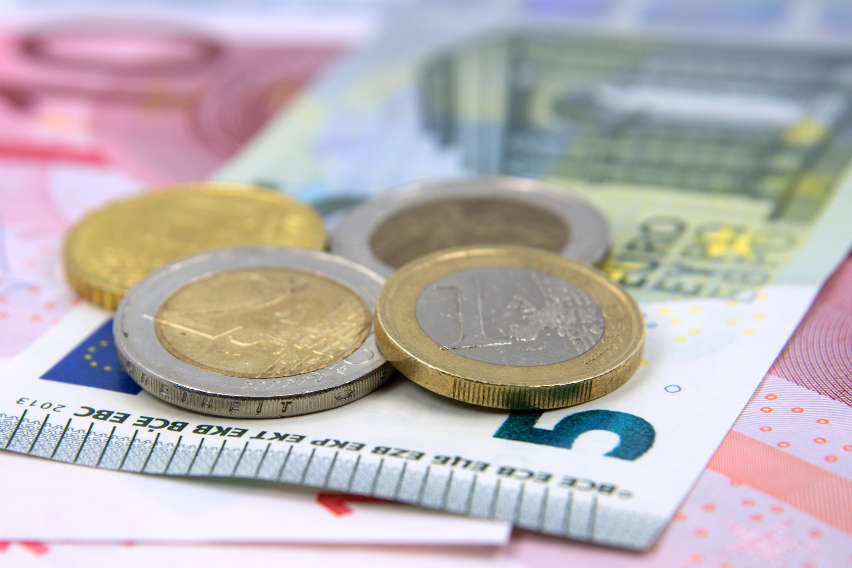 Auf einer Vielzahl von Euro-Scheinen liegen mehrere Münzen Auf einer Vielzahl von Euro-Scheinen liegen mehrere Münzen