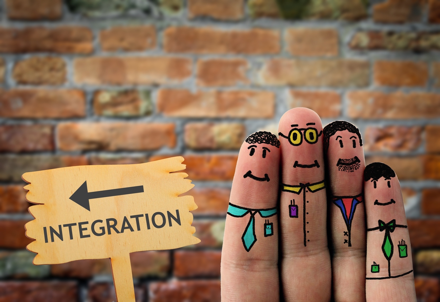 Auf Fingern werden Gesichter von Menschen gezeichnet und daneben steht ein Schild mit einem Pfeil und der Aufschrift Integration Auf Fingern werden Gesichter von Menschen gezeichnet und daneben steht ein Schild mit einem Pfeil und der Aufschrift Integration