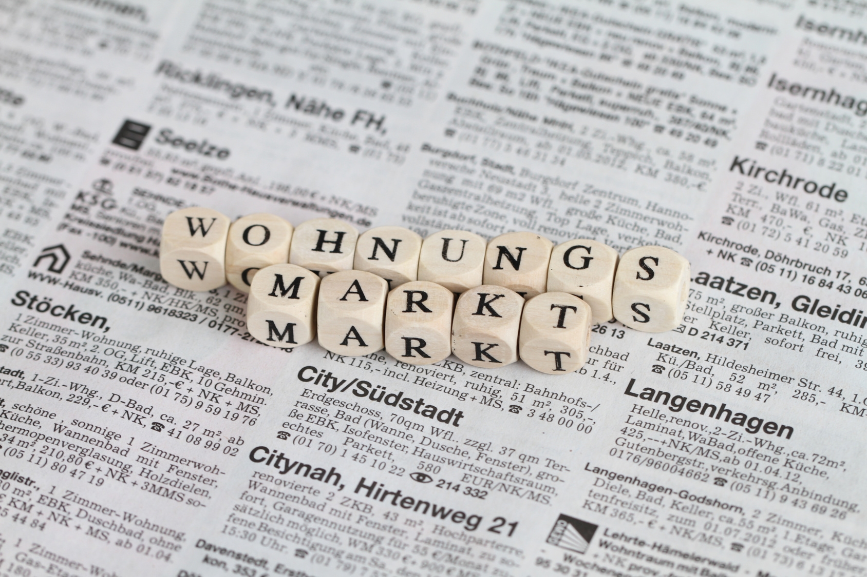 Buchstabenwürfel, die das Wort "Wohnungsmarkt" bilden auf einer Zeitung Buchstabenwürfel, die das Wort "Wohnungsmarkt" bilden auf einer Zeitung