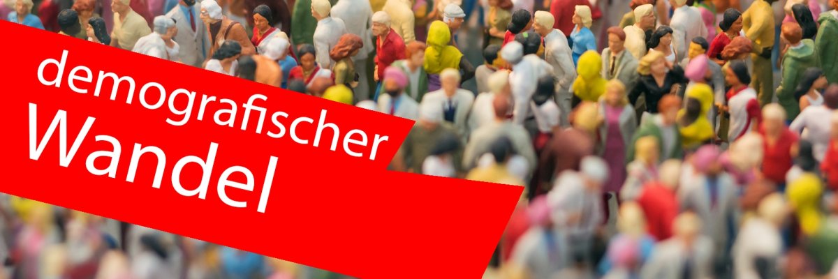 Vogelperspektive auf eine Masse von Miniaturfiguren von Menschen. Im vOrdergrund ein roter Balken mit der Aufschrift "demografischer Wandel". Vogelperspektive auf eine Masse von Miniaturfiguren von Menschen. Im vOrdergrund ein roter Balken mit der Aufschrift "demografischer Wandel".