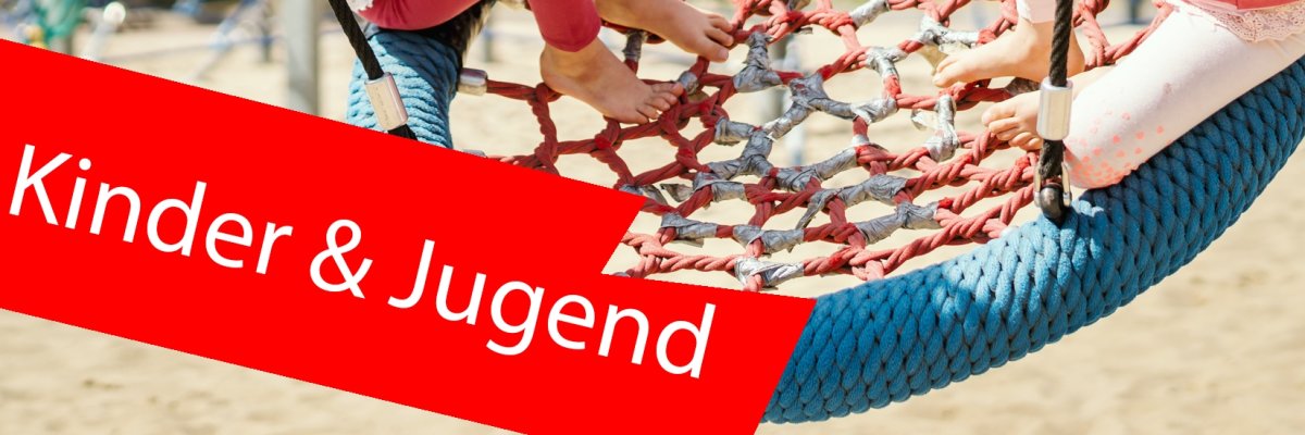 Zwei Kinder in einer großen und runden Schaukel am Spielplatz. Im Vordergrund ist ein roter Balken mit der Aufschrift "Kinder und Jugend". Zwei Kinder in einer großen und runden Schaukel am Spielplatz. Im Vordergrund ist ein roter Balken mit der Aufschrift "Kinder und Jugend".