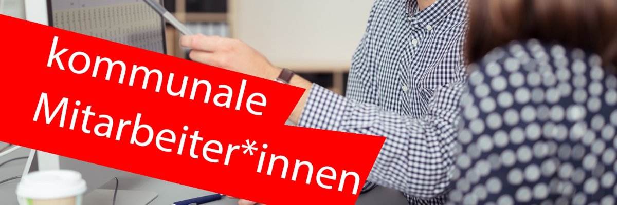 Mann erklärt vor einem Coomputer sitzend neben ihm einer Frau etwas. Dabei zeigt er mit einem Stift auf Zahlen auf dem Bildschirm. Im Vordergrund ein roter Balken mit der Aufschrift "kommunale Mitarbeiter*innen".