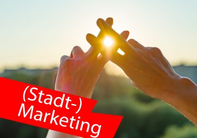 Finger bilden Hashtag-Symbol und zwischen den Fingern scheint die Sonne durch. Im Vordergrund ein roter Balken mit der Aufschrift "(Stadt-)Marketing". Finger bilden Hashtag-Symbol und zwischen den Fingern scheint die Sonne durch. Im Vordergrund ein roter Balken mit der Aufschrift "(Stadt-)Marketing".
